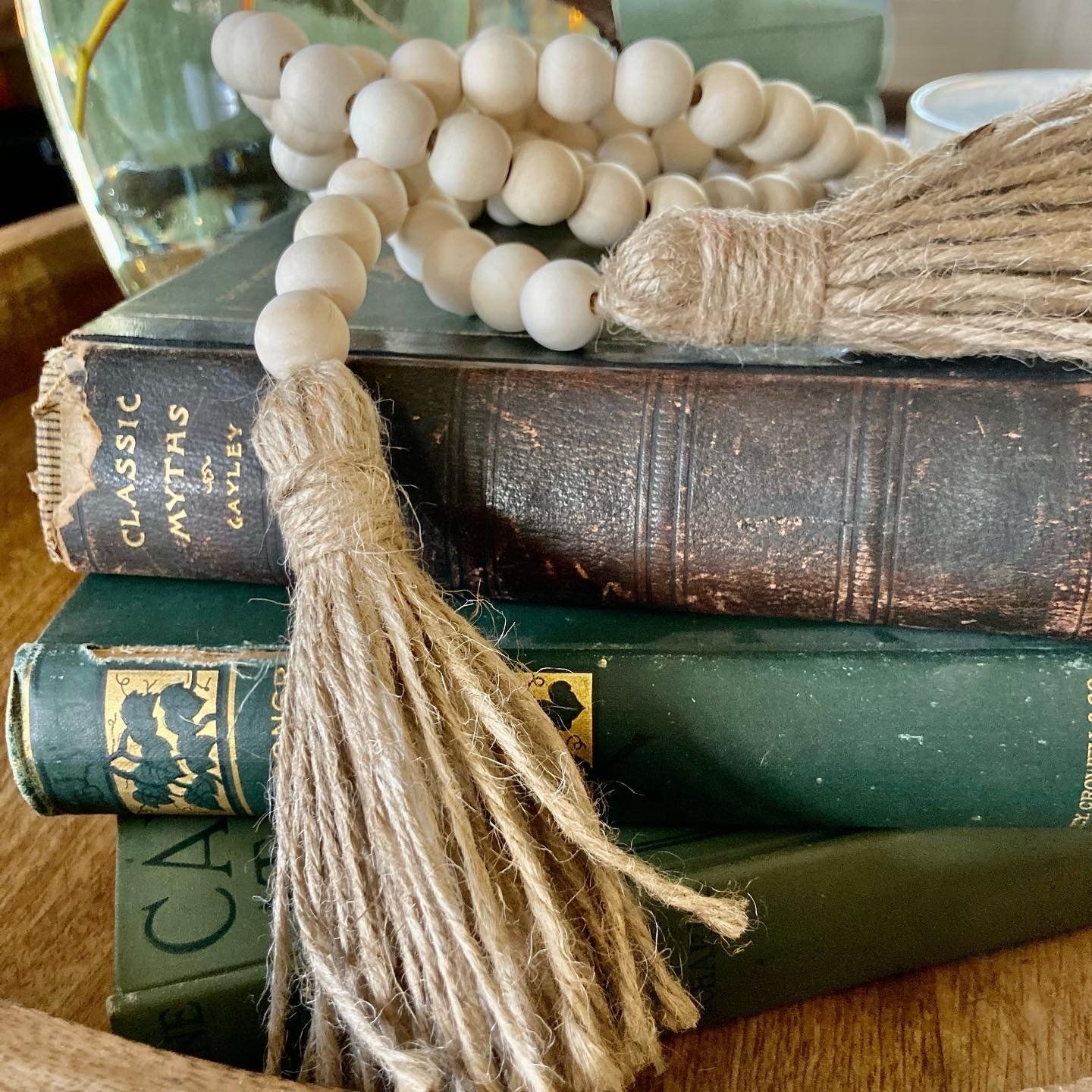 Wooden beads with burlap tassels rest on a stack of vintage books.