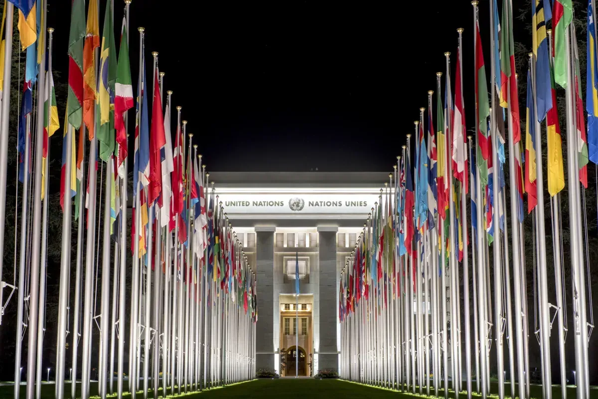 The UN Secretariat Building in New York City with a row of international flags displayed in the foreground.
