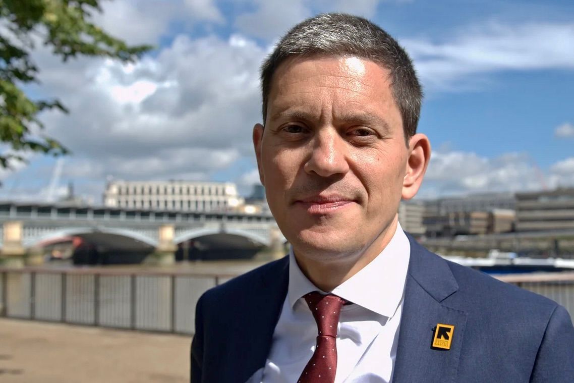 A woman smiling in front of a blue background featuring the European Union flag.