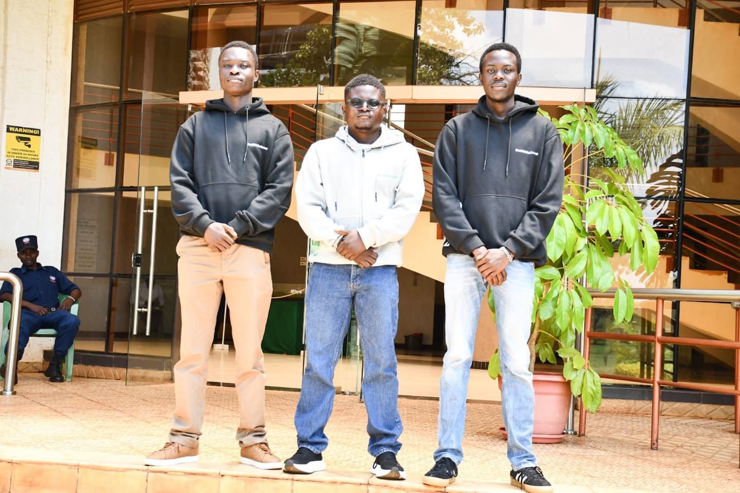 Three people sit at a table in a library, looking at a laptop together and discussing the information on the screen.