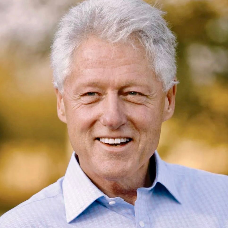 A headshot of Bill Clinton smiling against a blurred, warm-toned outdoor background.