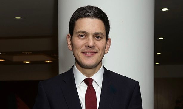 A woman smiling in front of a blue background featuring the European Union flag.