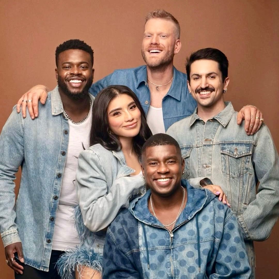 Five smiling people pose against a solid brown background, wearing denim shirts and jackets.