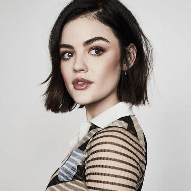 Lucy Hale poses with a chin-length dark bob haircut, wearing a striped shirt with a collar against a light background.