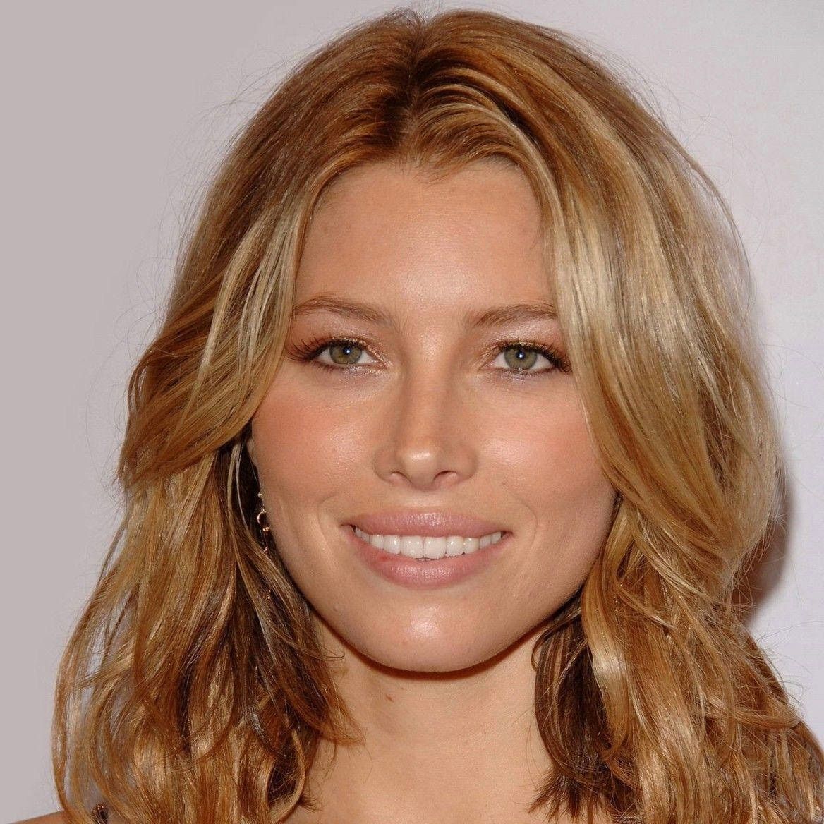 Portrait of a smiling person with wavy, golden-brown hair, centered against a plain white background.