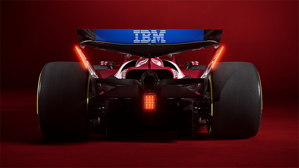 A red Ferrari Formula 1 car viewed from the rear, with illuminated brake lights and an IBM logo on the rear wing.