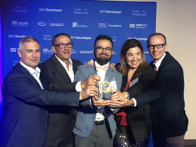 Five people in professional attire smiling while holding an award against a blue IBM Developer backdrop.