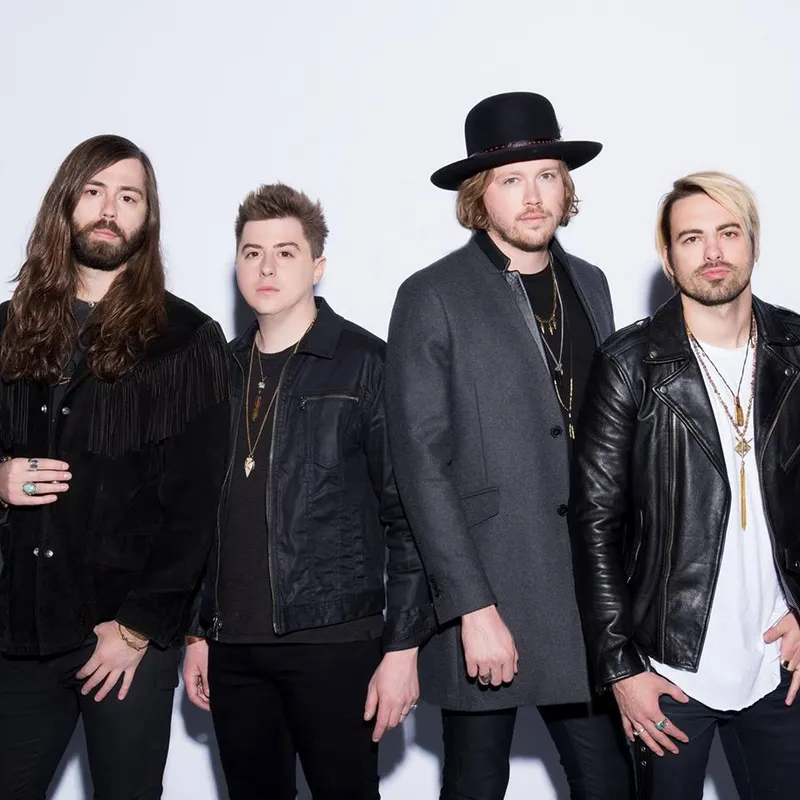 A studio portrait of the four members of the band A Rocket to the Moon standing in a row against a white background.