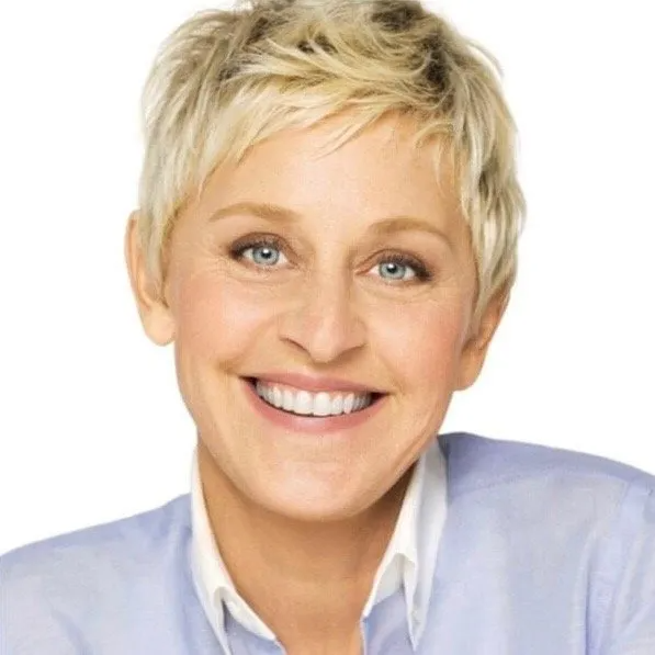 Headshot of Ellen DeGeneres smiling, featuring her signature blonde pixie cut, wearing a light blue collared shirt.