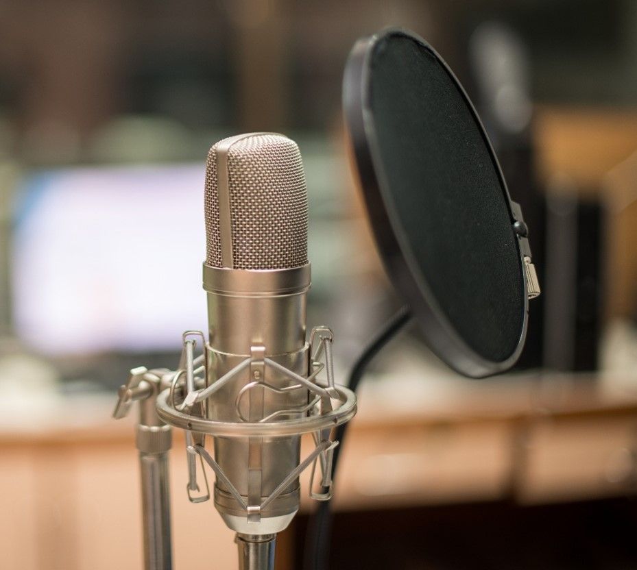 Silver microphone with a pop filter in a recording studio.
