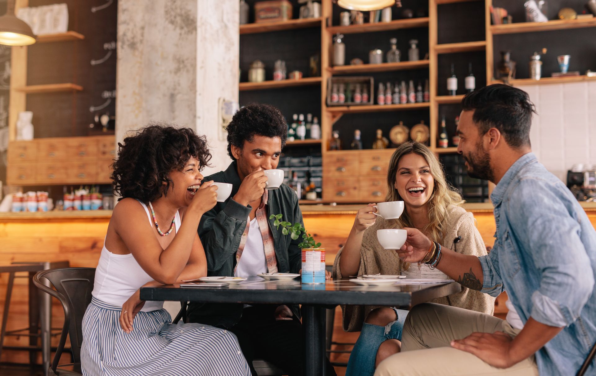 A group of friends sit at a table drinking coffee on international coffee day