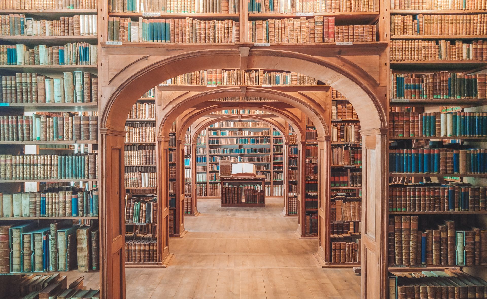 Arches of library bookshelves with books stacked on them