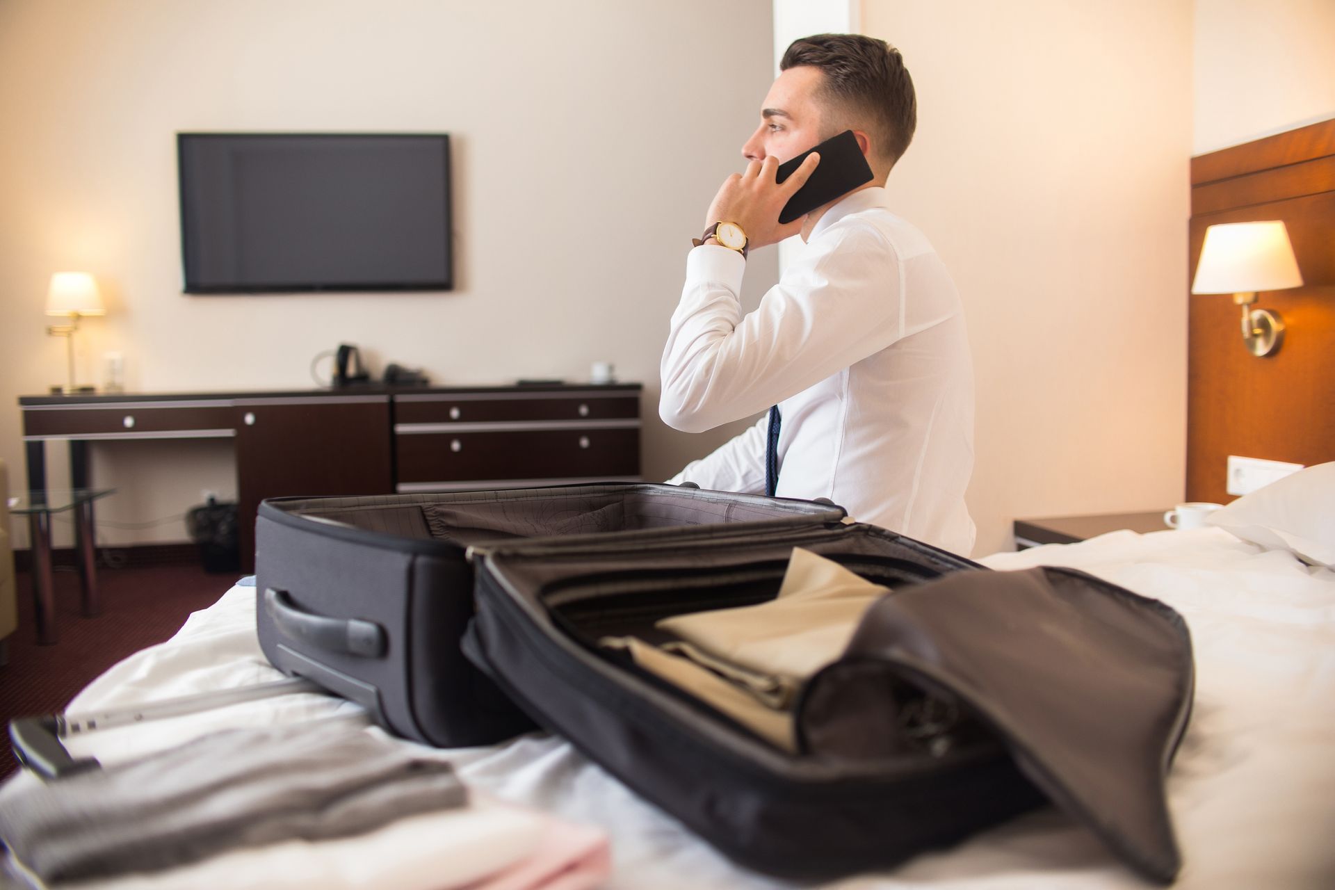 working professional sat in serviced accommodation unpacking his suitcase