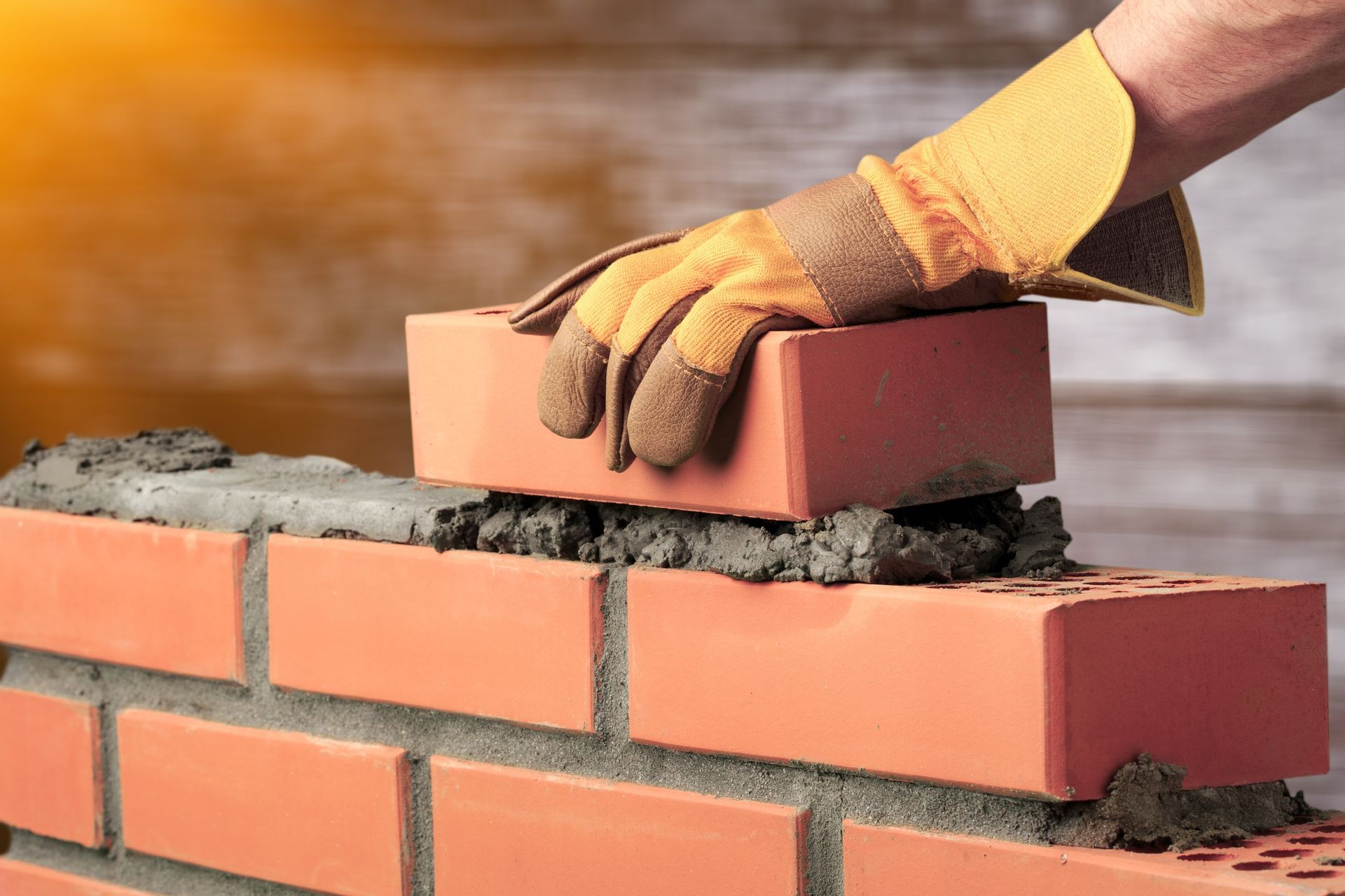 a person wearing gloves is putting a brick on top of another brick