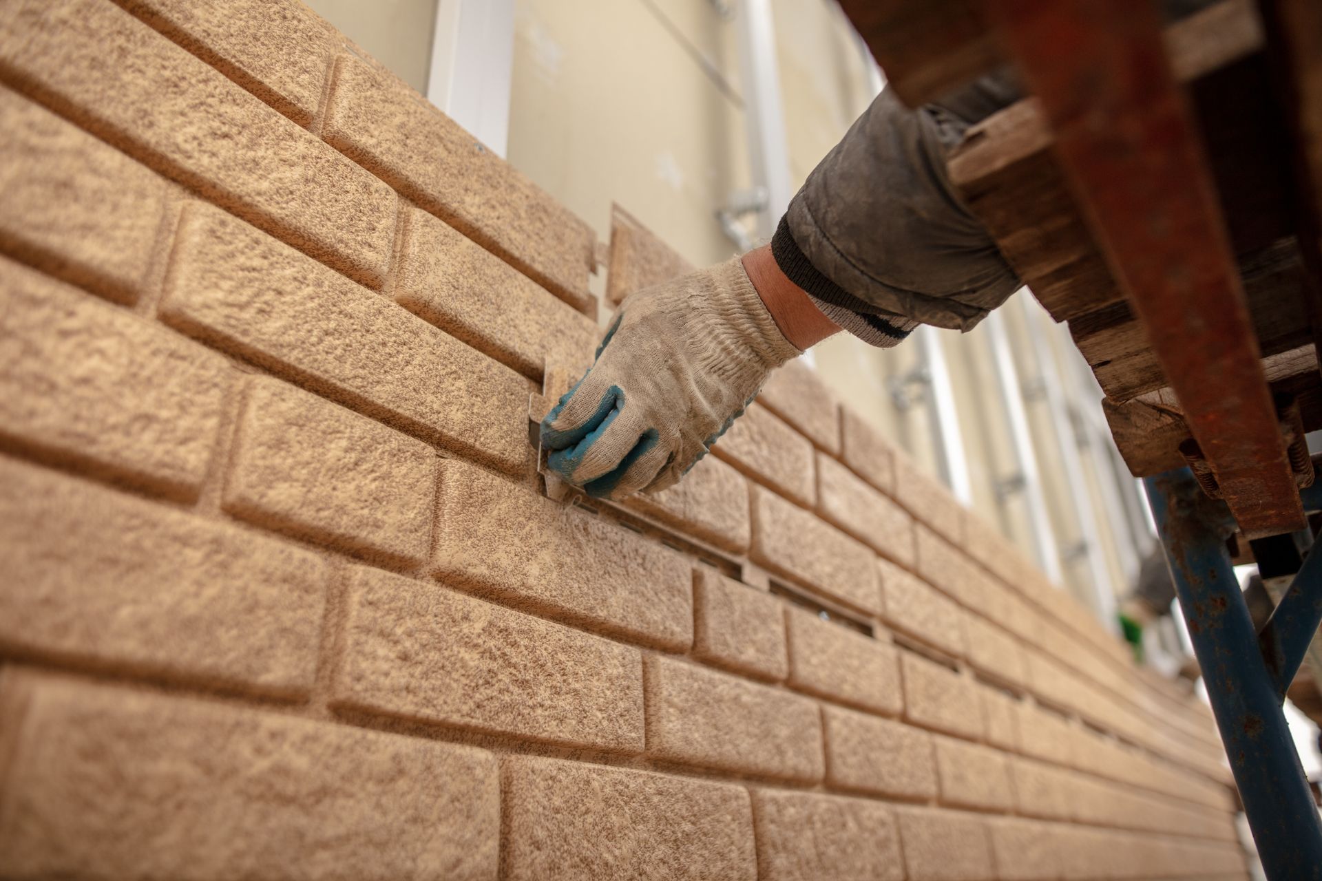 a person wearing gloves is working on a brick wall