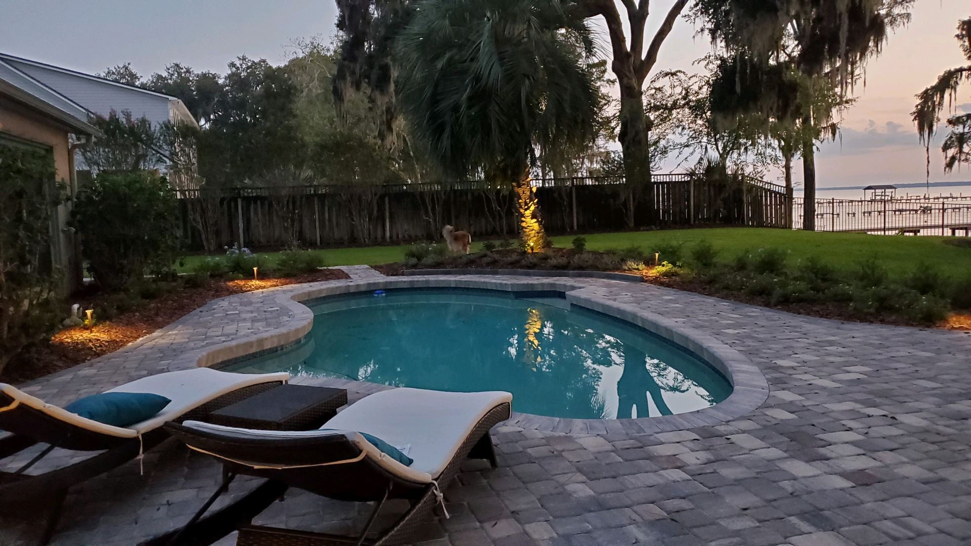 There is a large swimming pool in the backyard of a house.