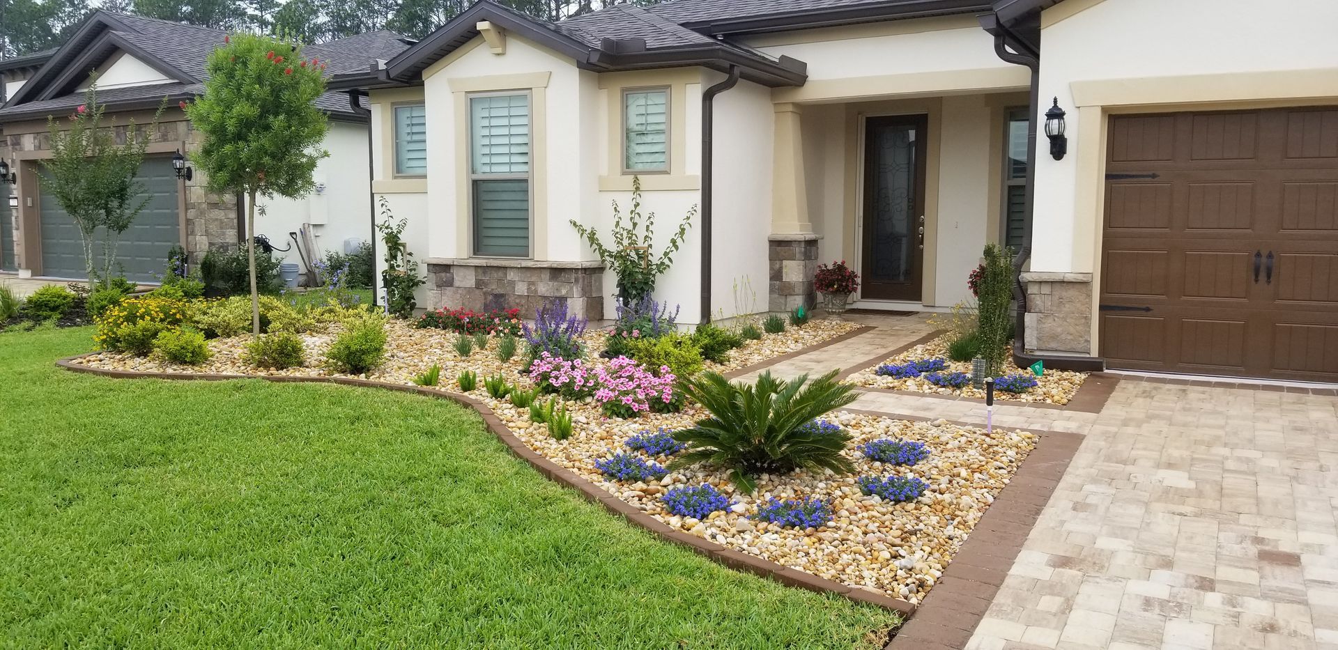 A house with a lush green lawn and a brick driveway in front of it.