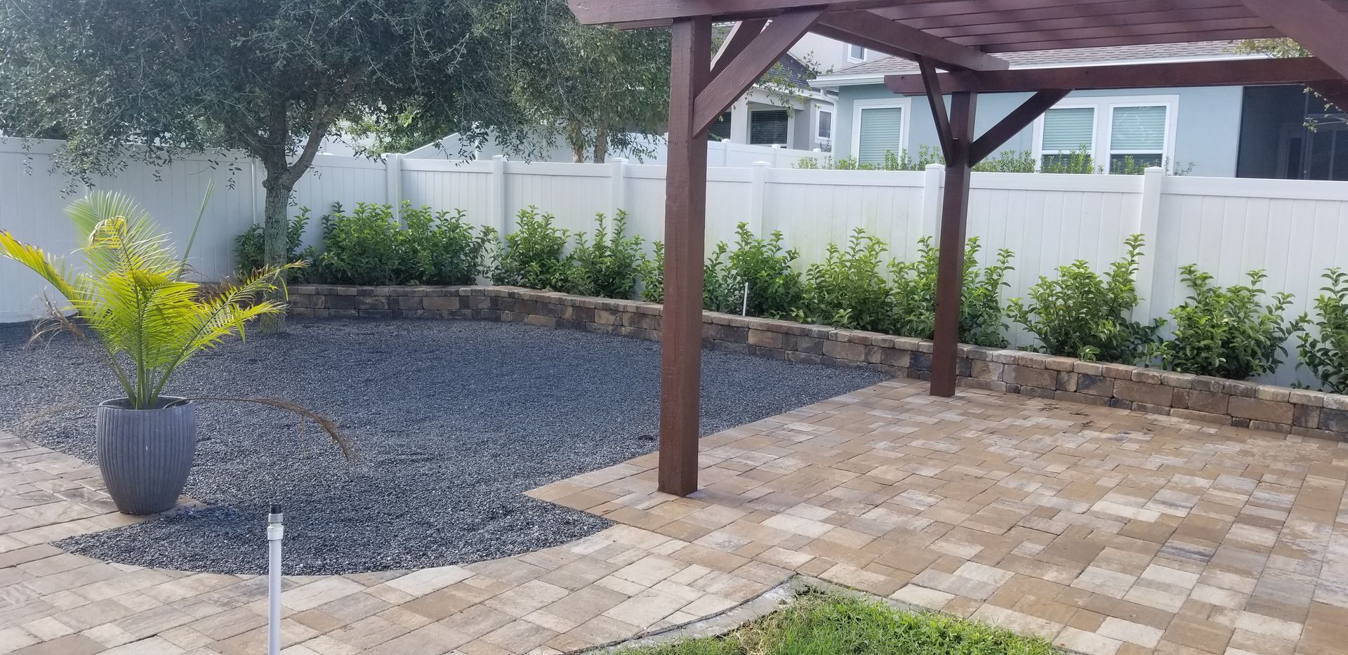 A patio with a pergola and a potted plant in the middle.