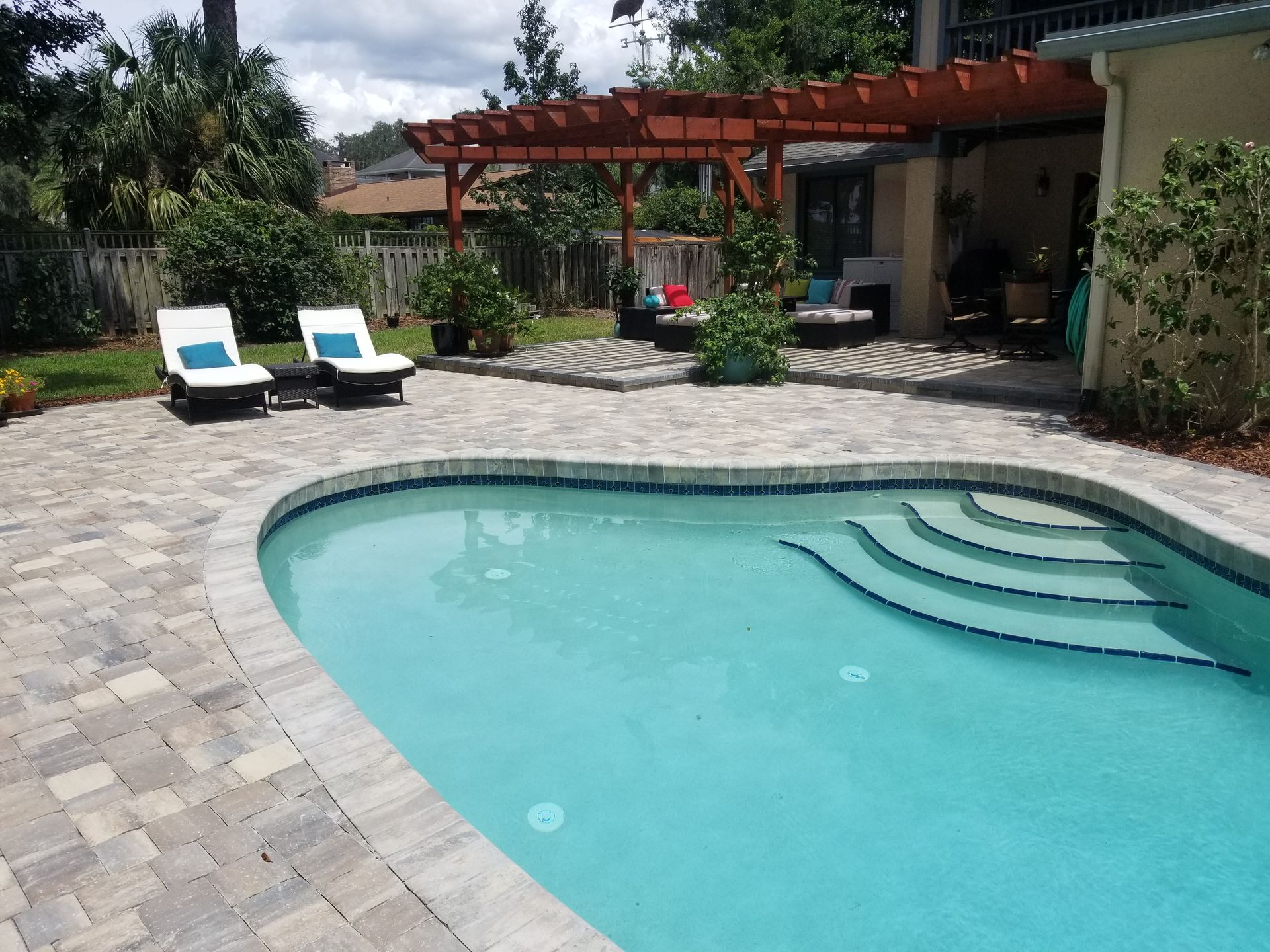 A large swimming pool surrounded by chairs and a pergola