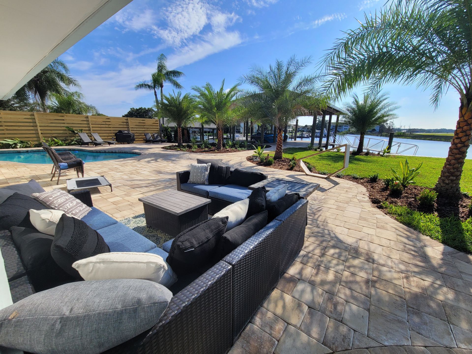 A patio with a lot of furniture and a pool in the background