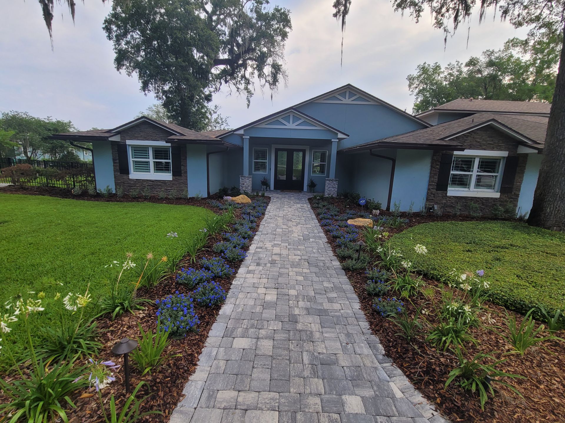 A blue house with a brick walkway leading to it.