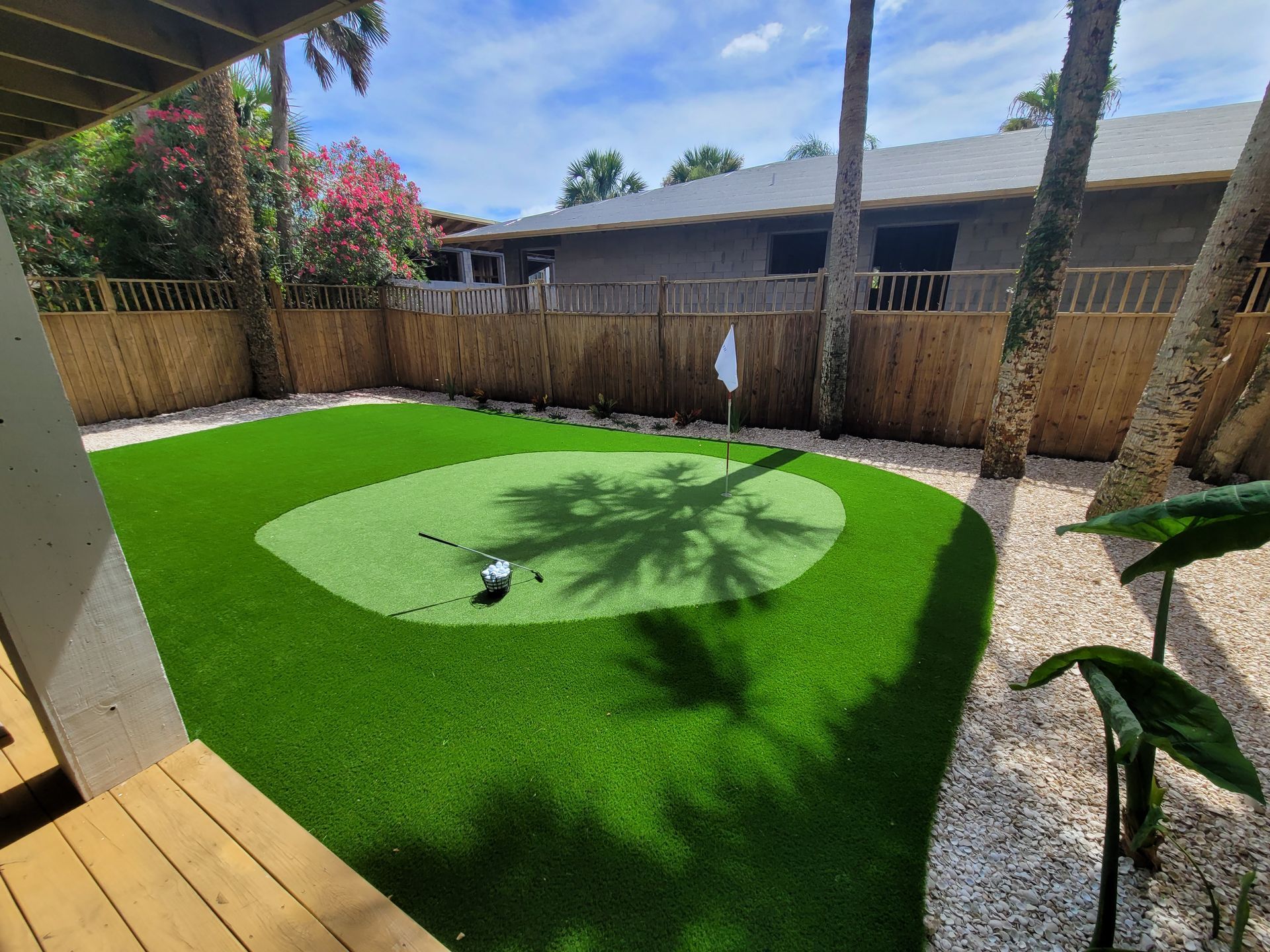 A backyard with a putting green and a wooden fence.