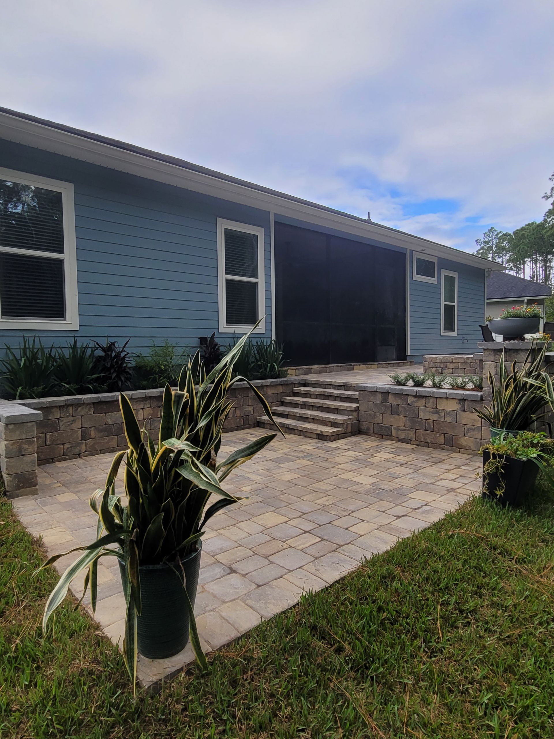 A blue house with a patio and potted plants in front of it.
