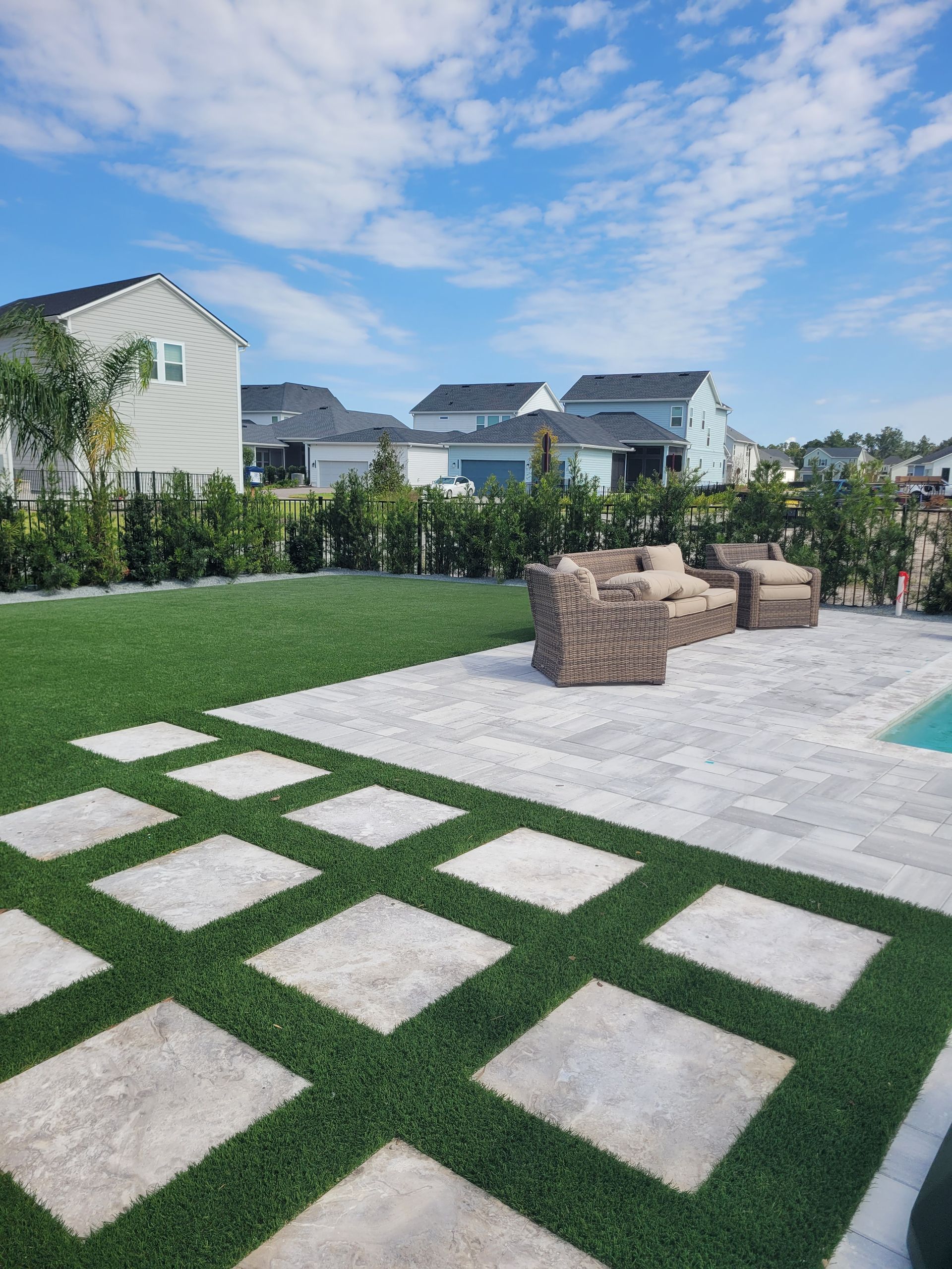 A patio with a swimming pool and a lawn in the background.