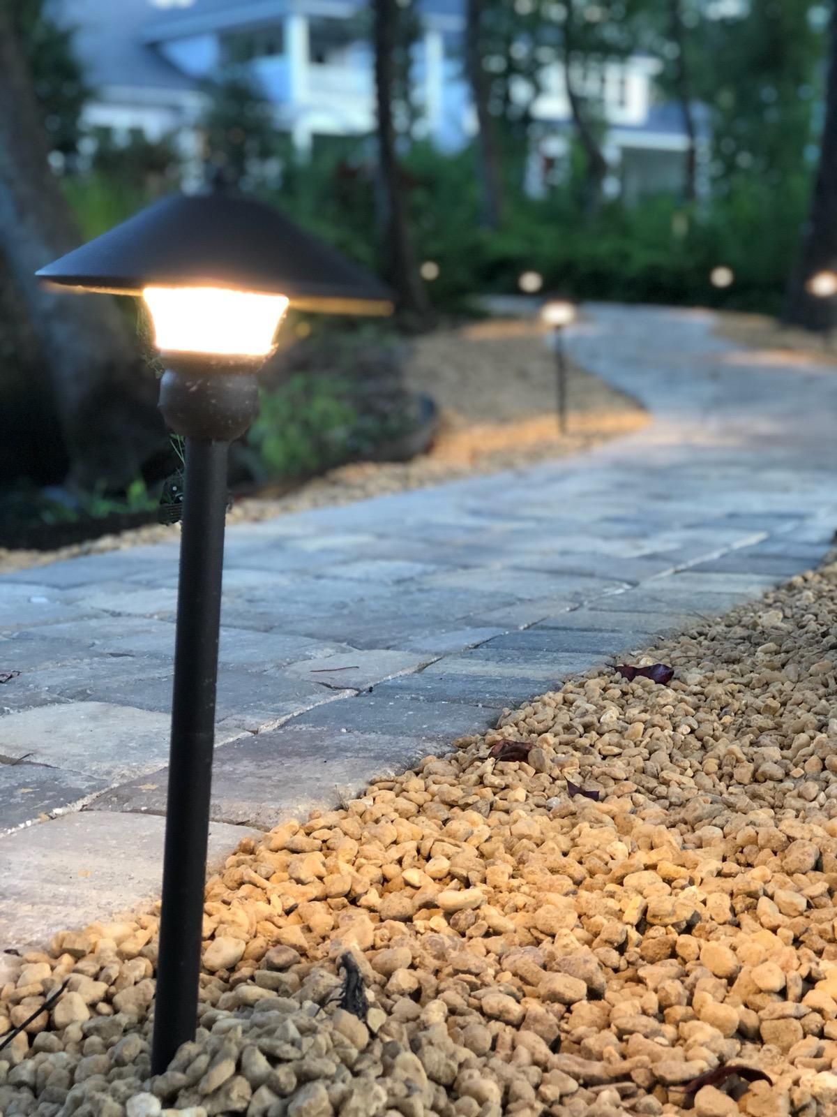A brick walkway with a light on the side of it.