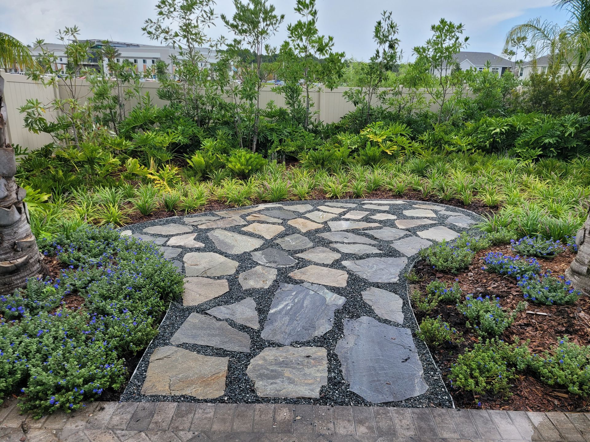 A stone walkway in a garden surrounded by trees and bushes.