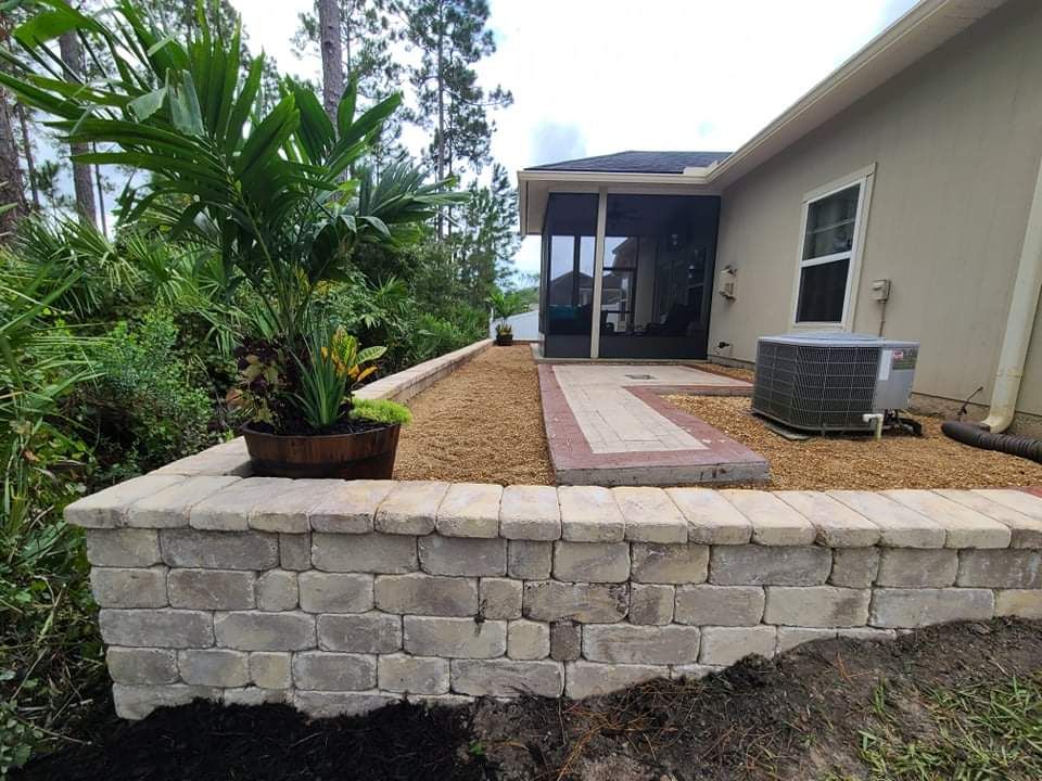 A brick wall surrounds a patio area in front of a house.