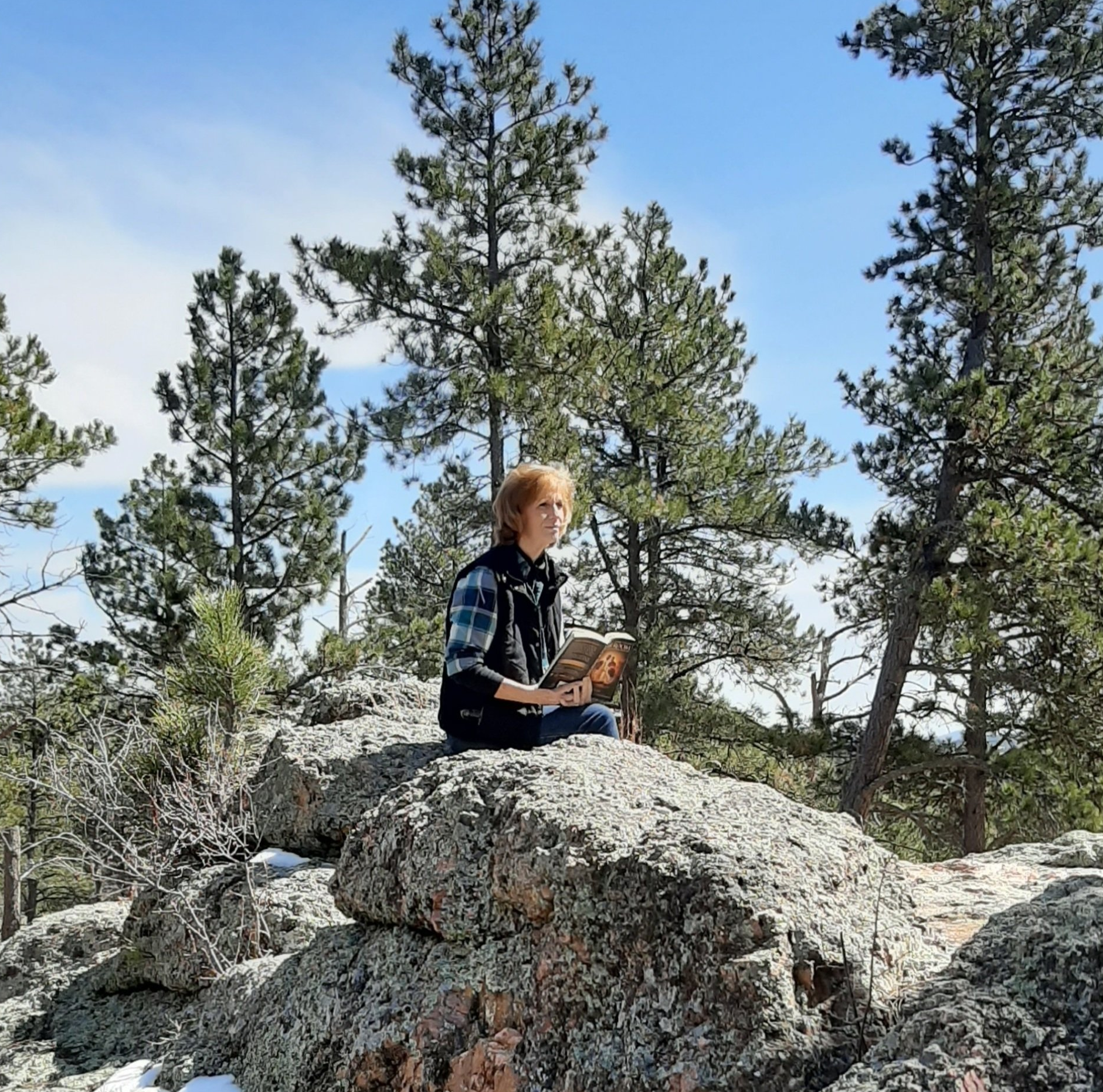 Trish Ladner sitting on a rock reading a book