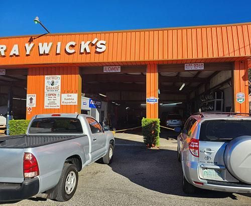 Graywick's auto repair shop exterior; two vehicles parked in front of open bays. Orange facade, sunny day.