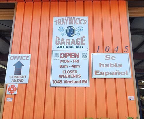 Exterior of Traywick's Garage with orange siding, signs for the office, hours, and Spanish-speaking services.