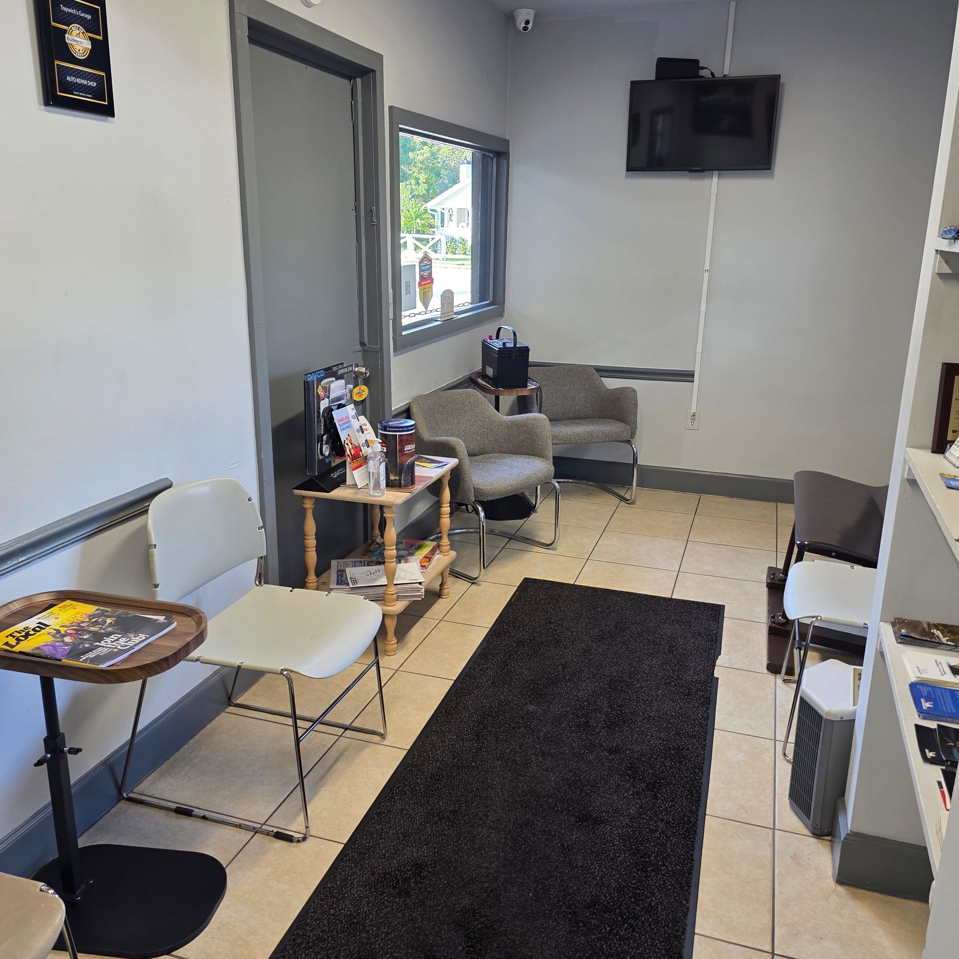 Waiting room with chairs, rug, table with snacks, and a TV.