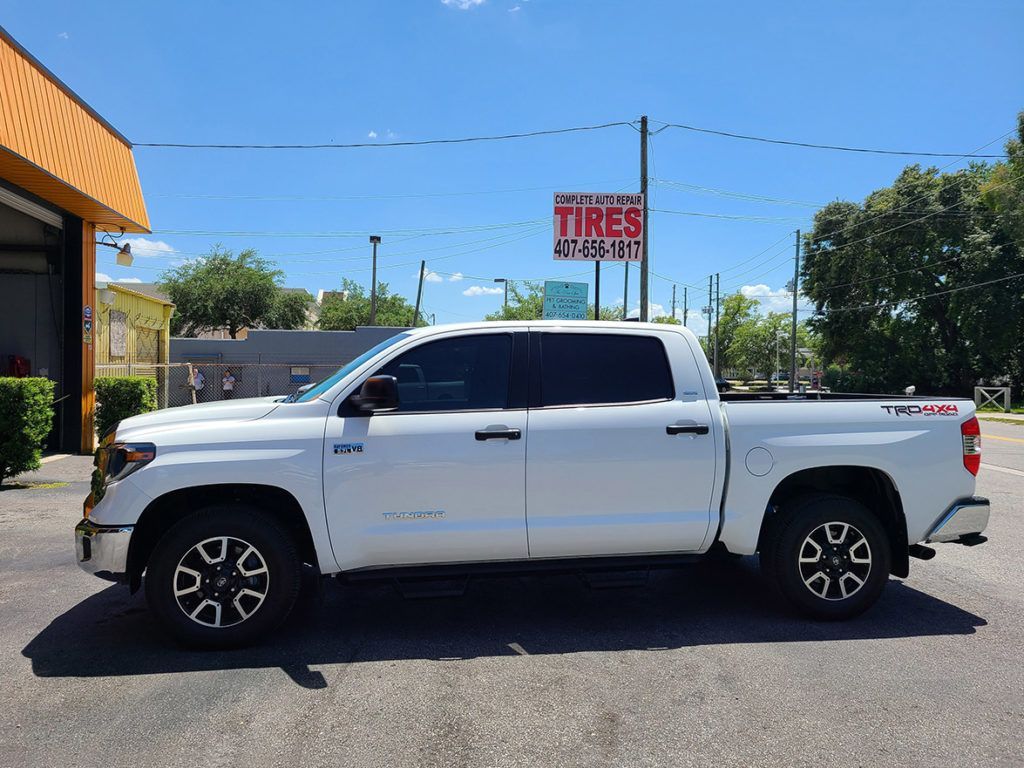 White Toyota Tundra pickup truck parked outside a tire shop on a sunny day.