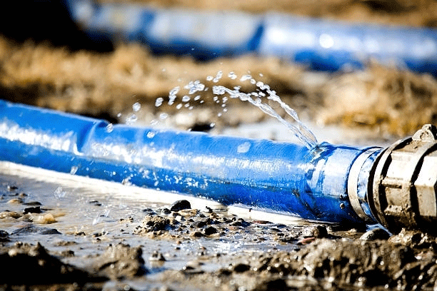 Blue pipe leaking water onto muddy ground.