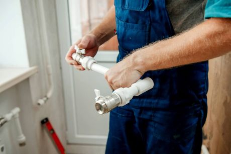 A plumber is fixing a pipe in a bathroom