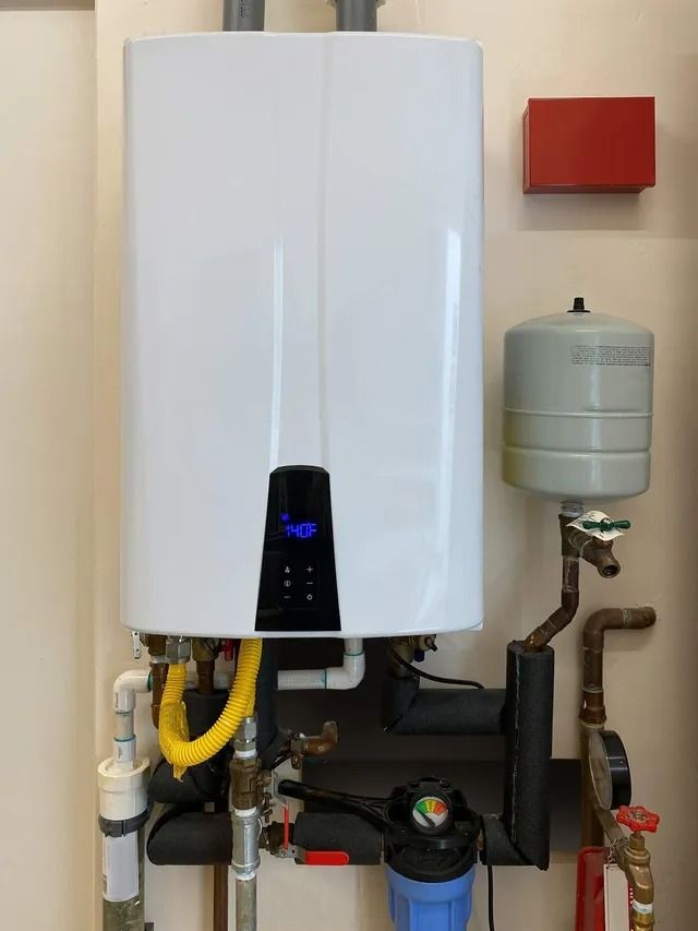 A white water heater is hanging on a wall next to pipes.