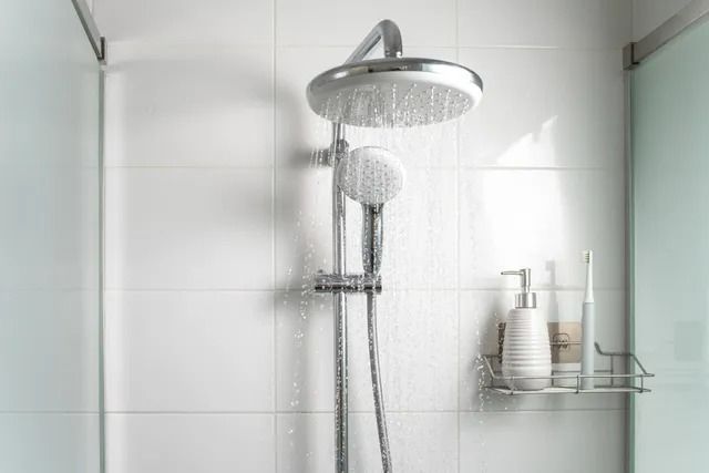There is a shower head in the shower with water coming out of it.