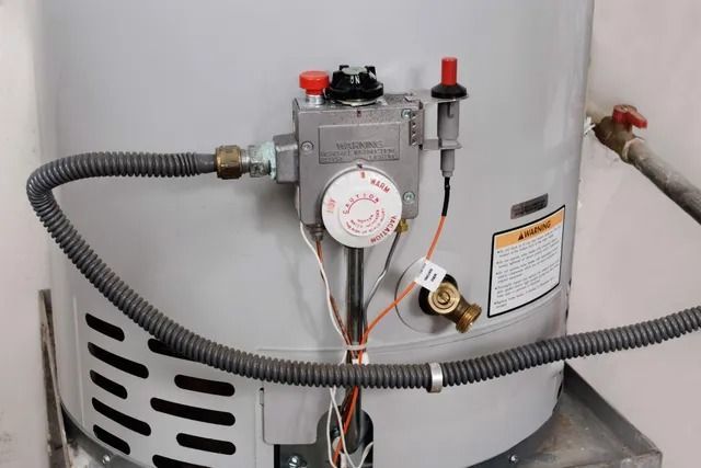 A close up of a water heater with a hose attached to it.