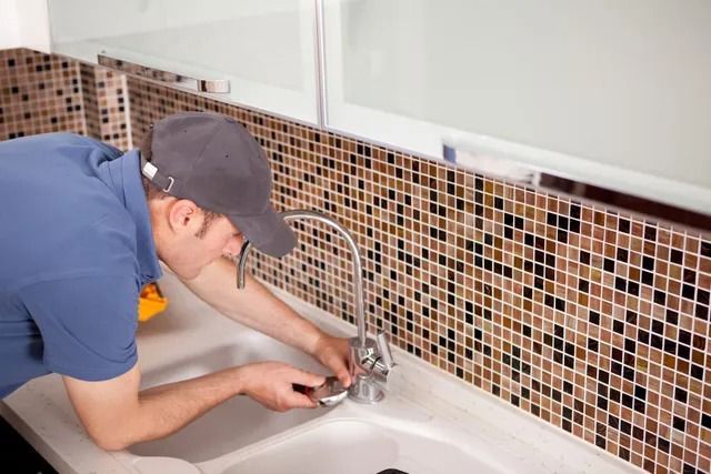 A man is fixing a faucet in a bathroom.