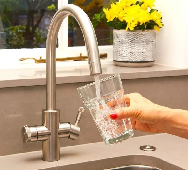 A person is filling a glass with water from a faucet