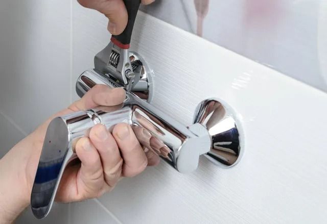 A person is fixing a shower head with a wrench
