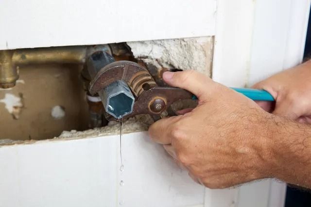 A man is fixing a pipe with a wrench.