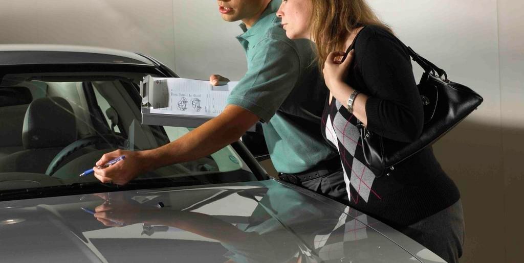 A man and a woman are looking at a car in a showroom.