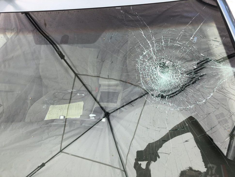 A person is taking a picture of a broken windshield.