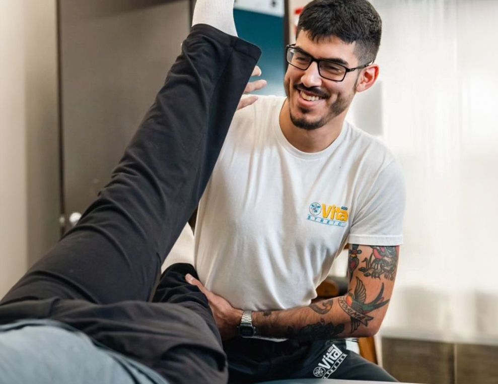 A man is stretching a person 's leg on a table.