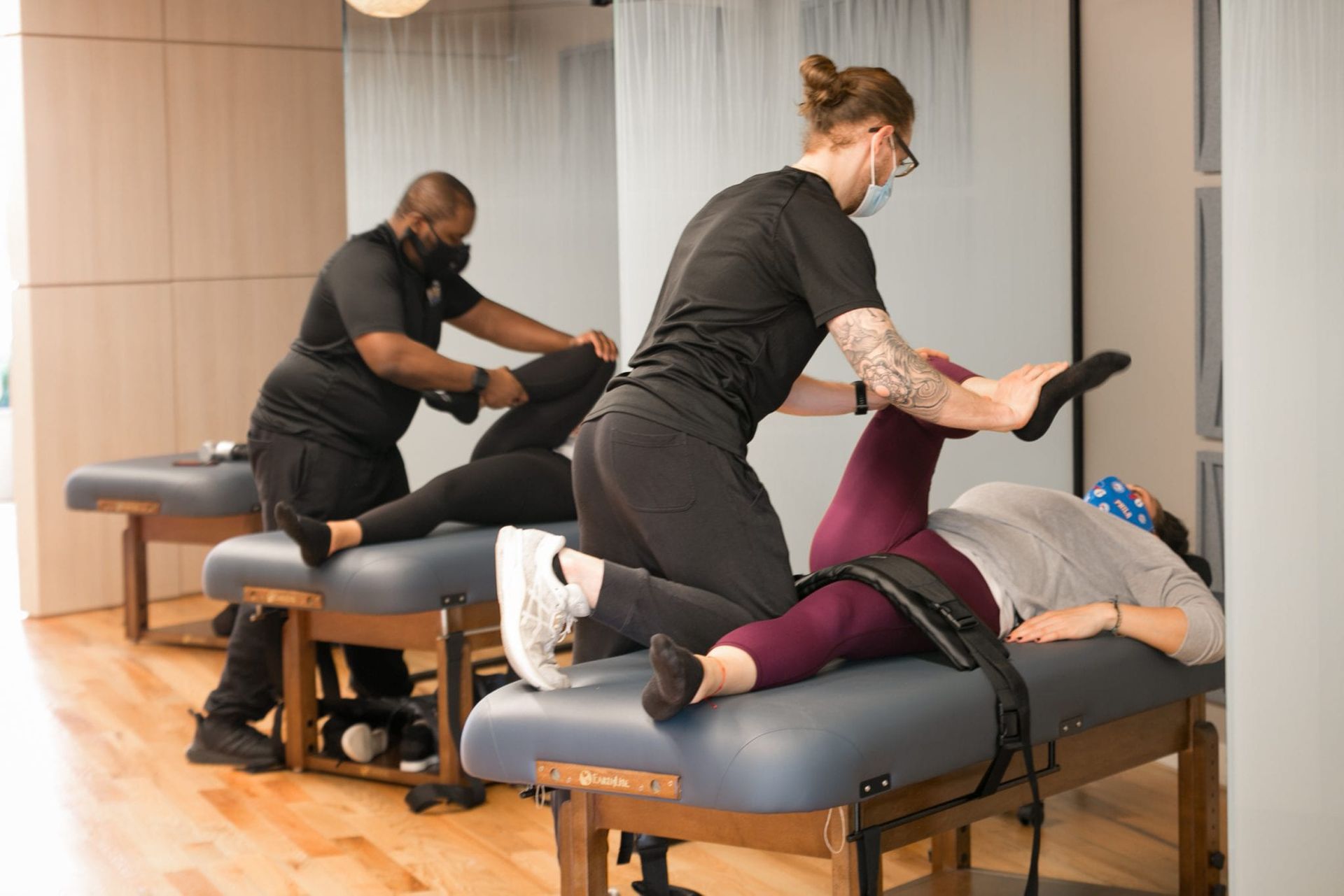 A woman is laying on a massage table while a man stretches her legs.