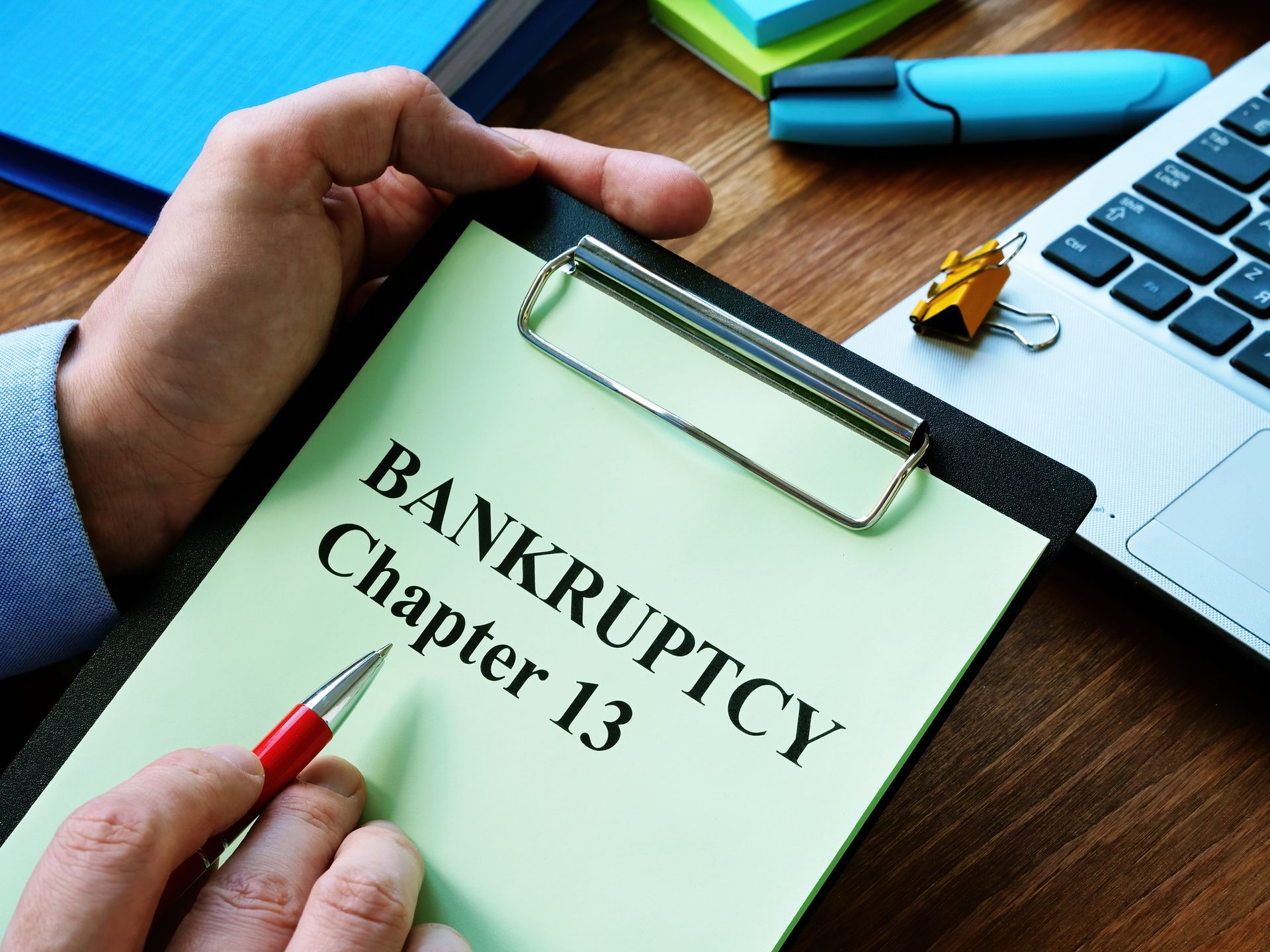 A person is writing on a clipboard that says bankruptcy chapter 13